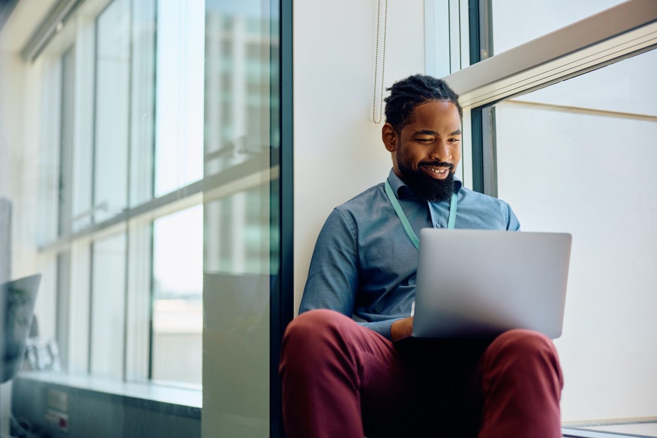 happy-black-entrepreneur-using-laptop-by-the-window-in-the-office-.jpg